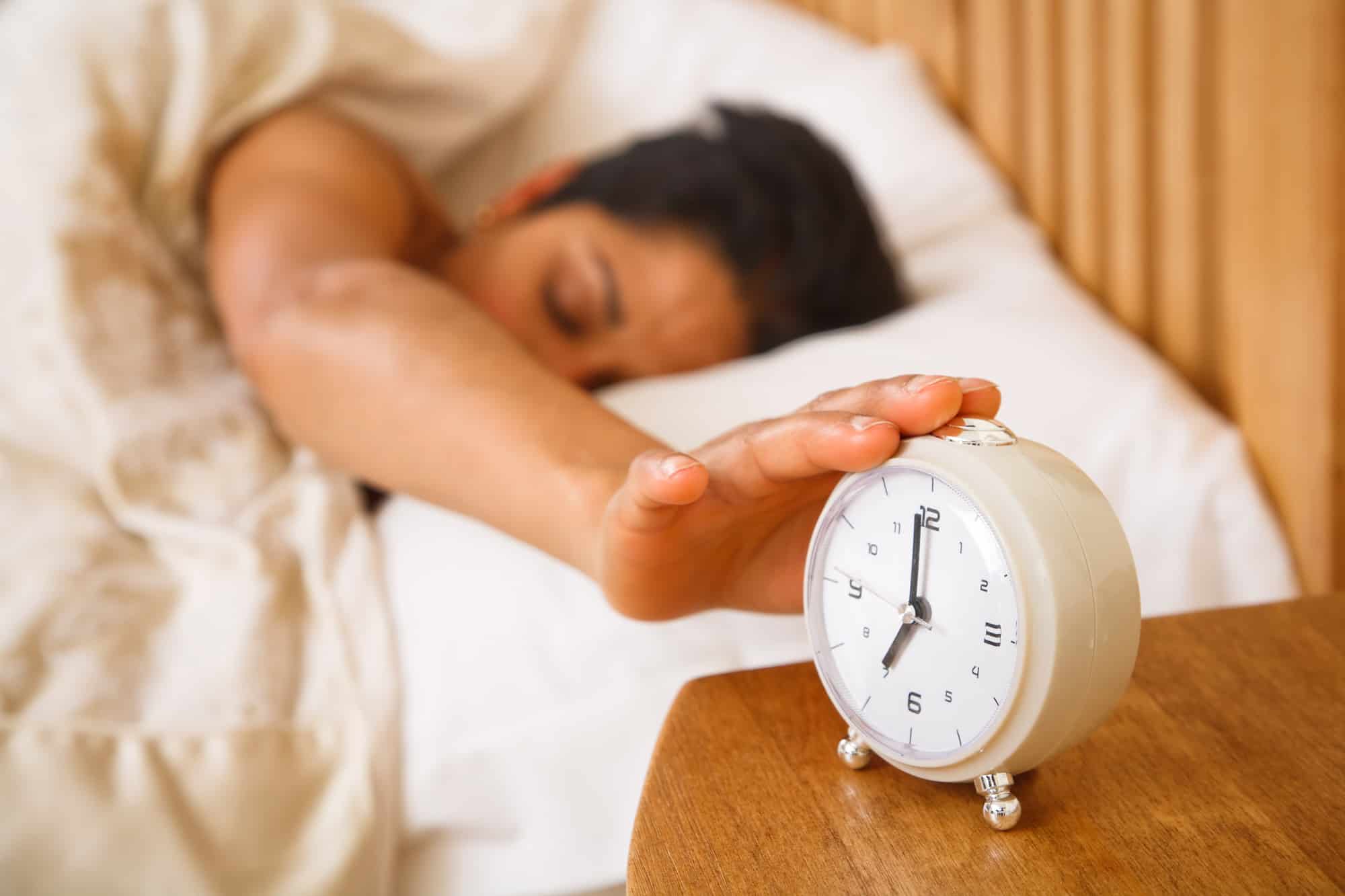 woman turning off alarm clock