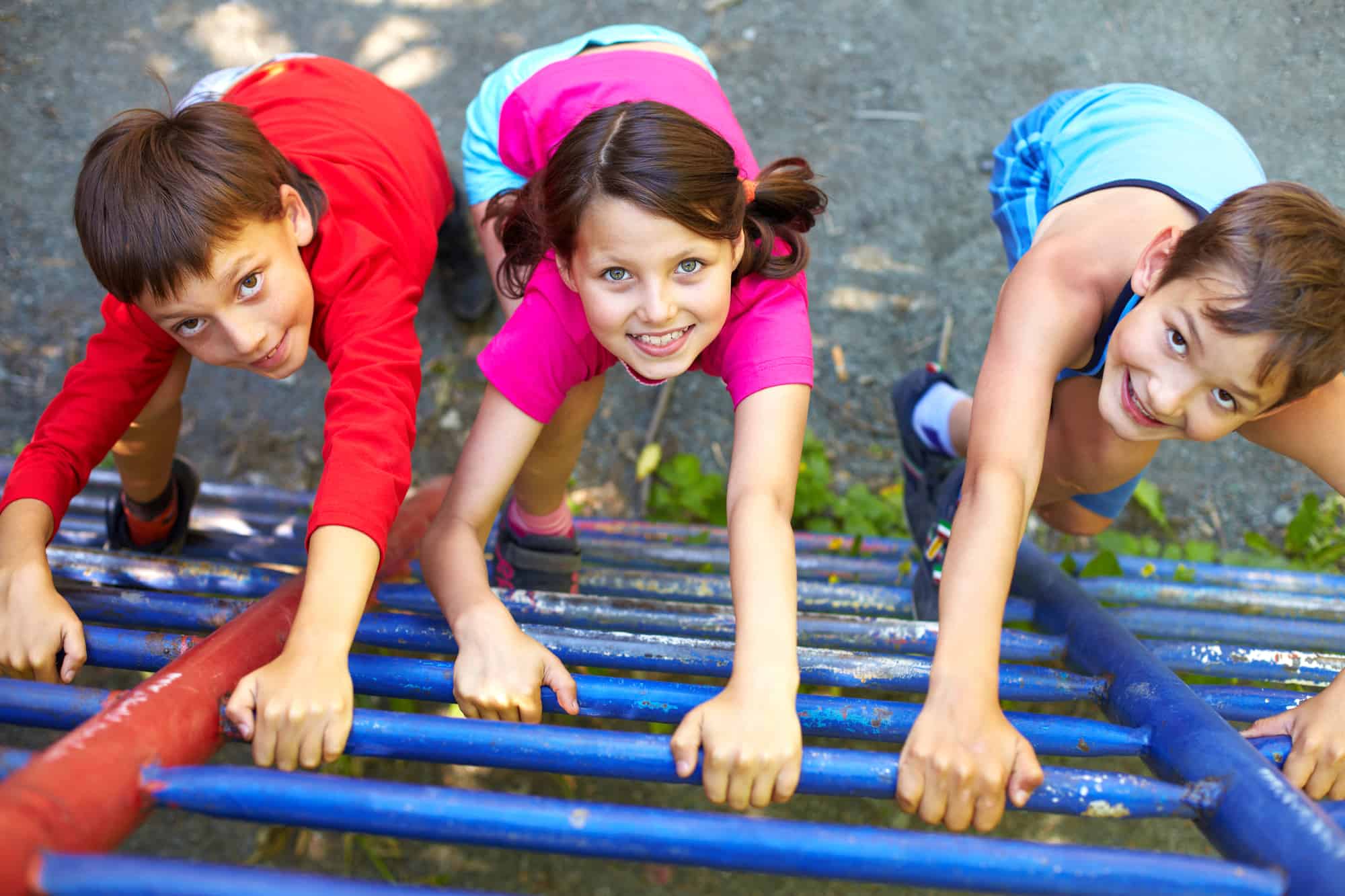 Three kids climbing a ladder at a playground