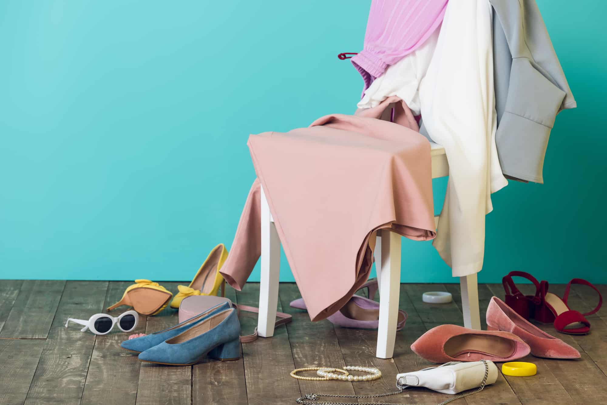 Messy room with elegant fashionable clothes and shoes on chair