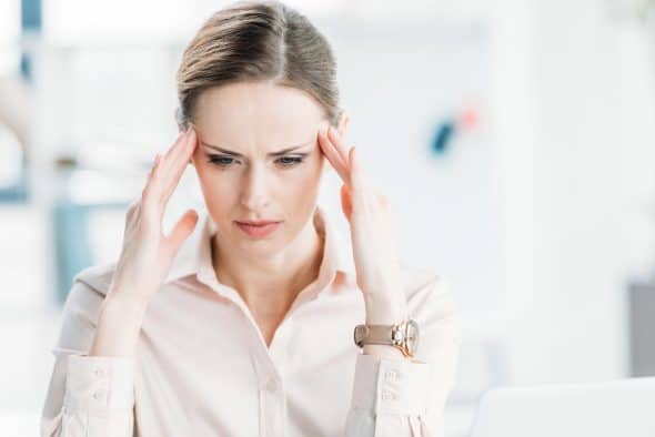 Tired pensive businesswoman with hands on head looking down