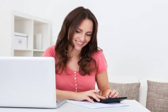 Woman using laptop and calculator