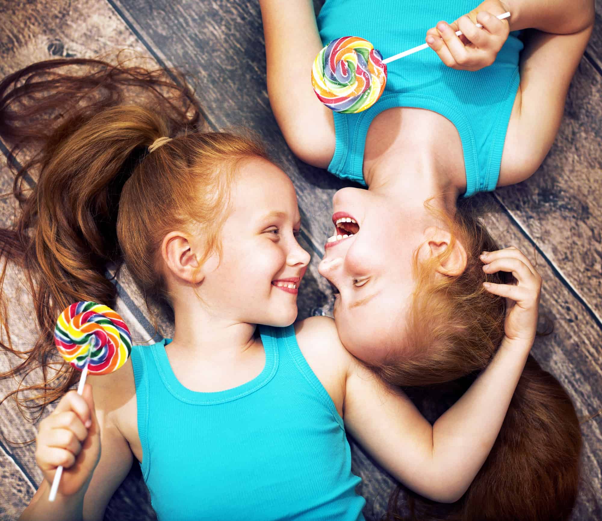 twin sisters holding colorful lollipops