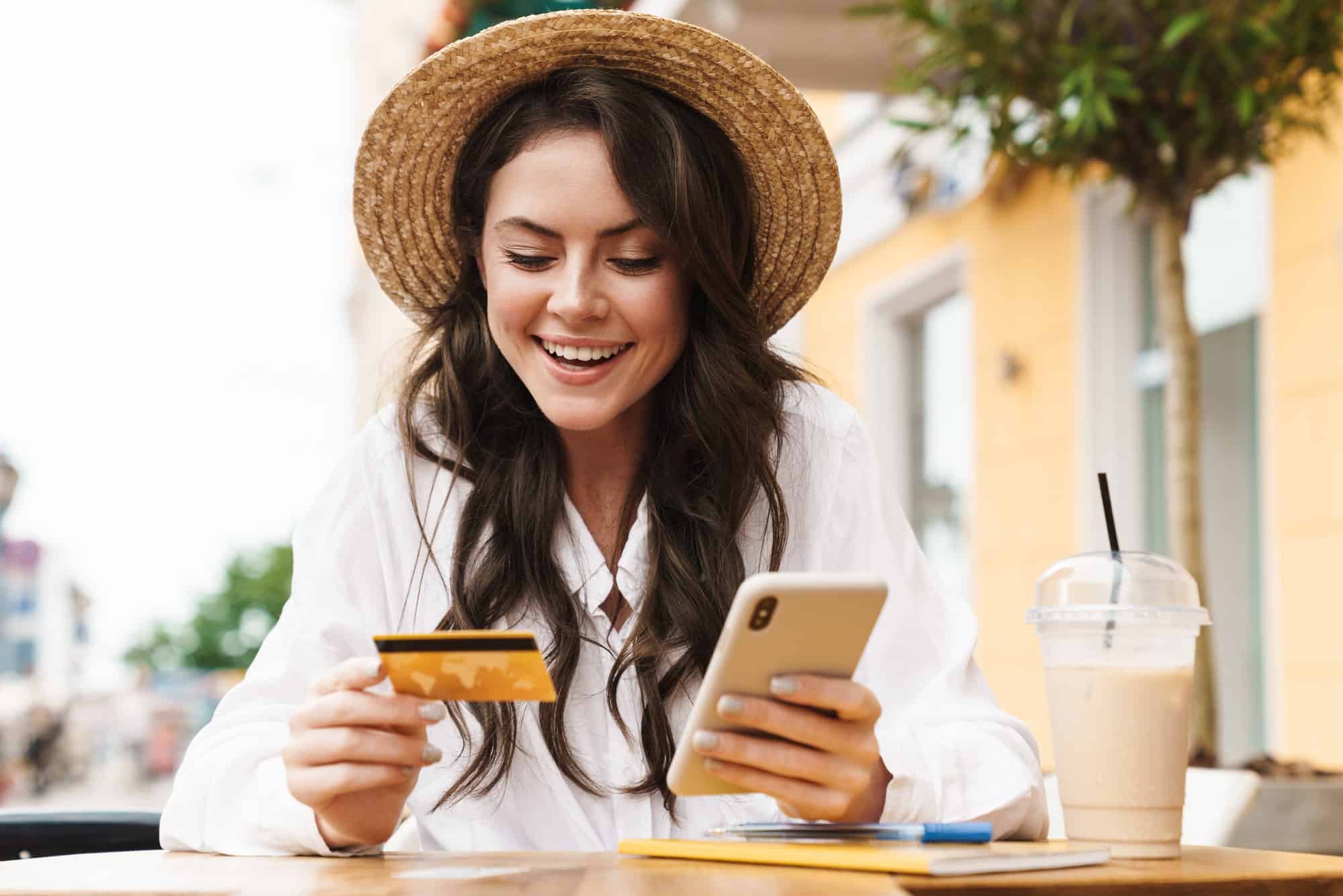 woman smiling with credit card and cell phone and coffee